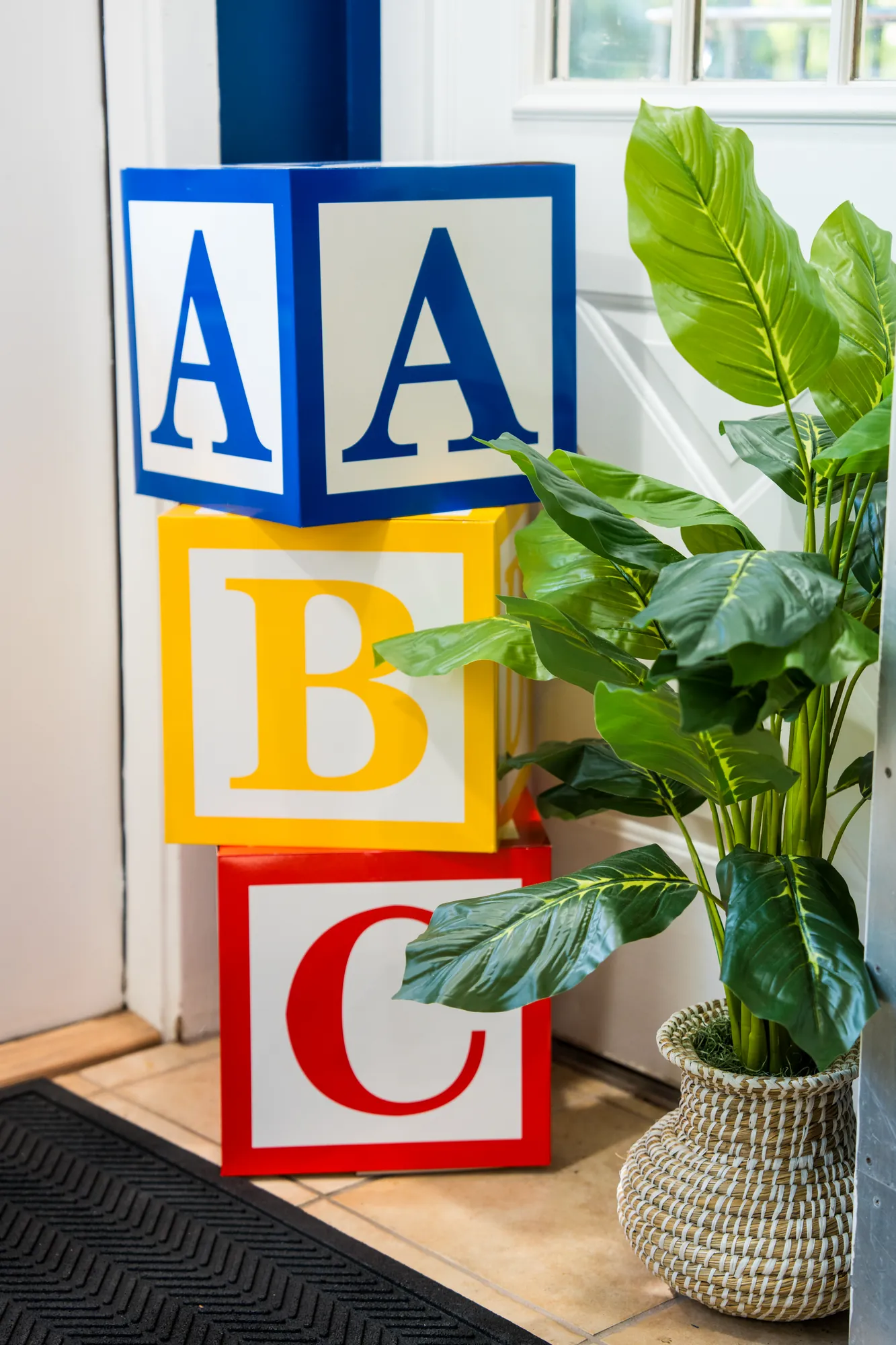 Oversized ABC blocks and a potted plant by the entrance