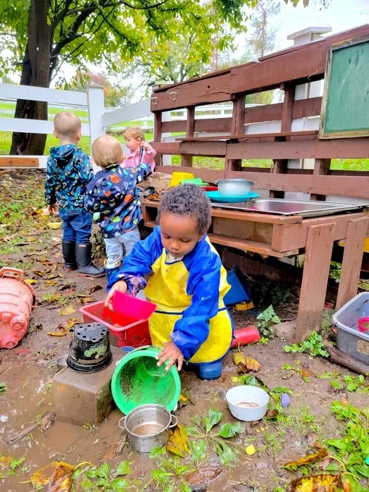 Children exploring an outdoor water and mud play table