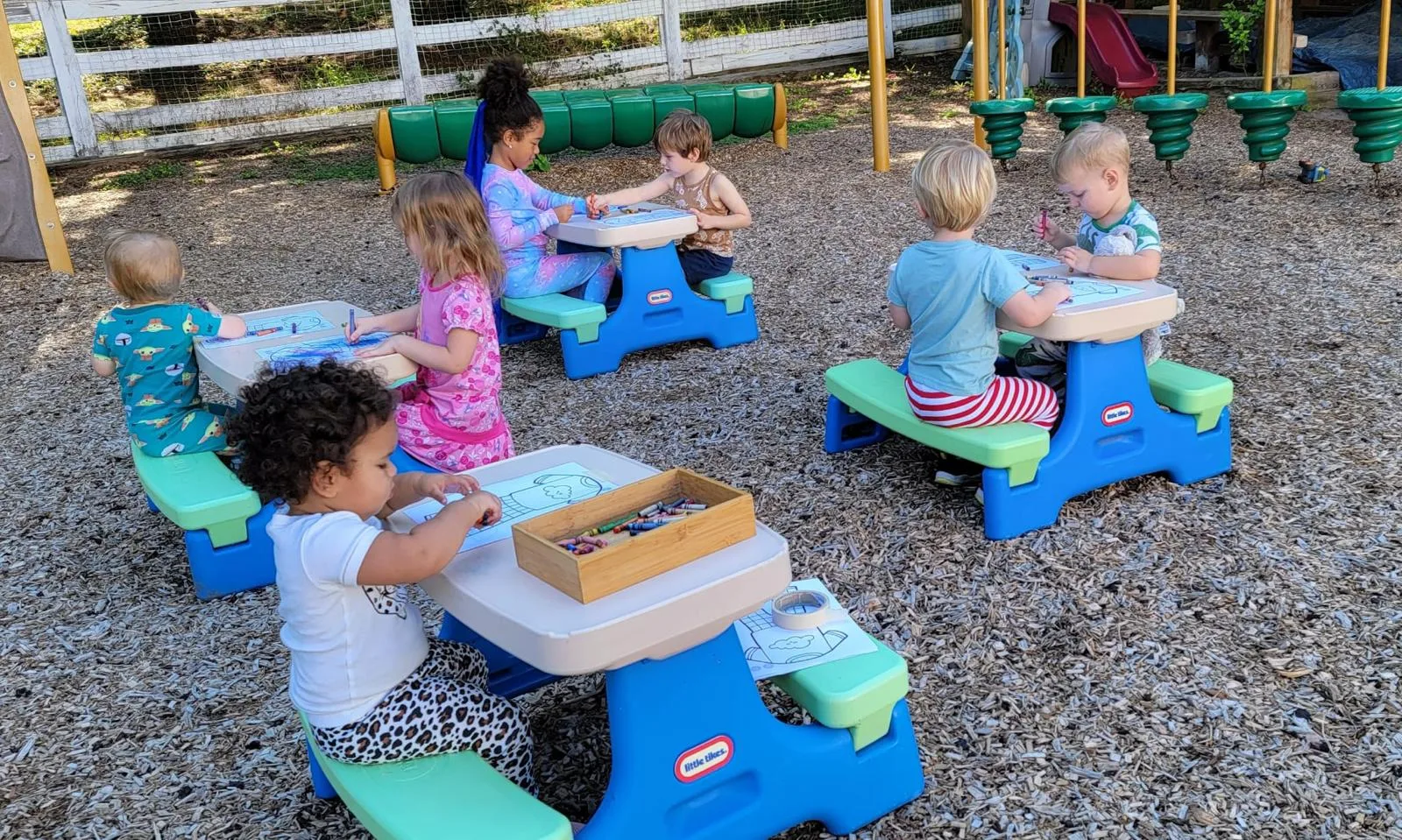 Children drawing at picnic tables in the play yard