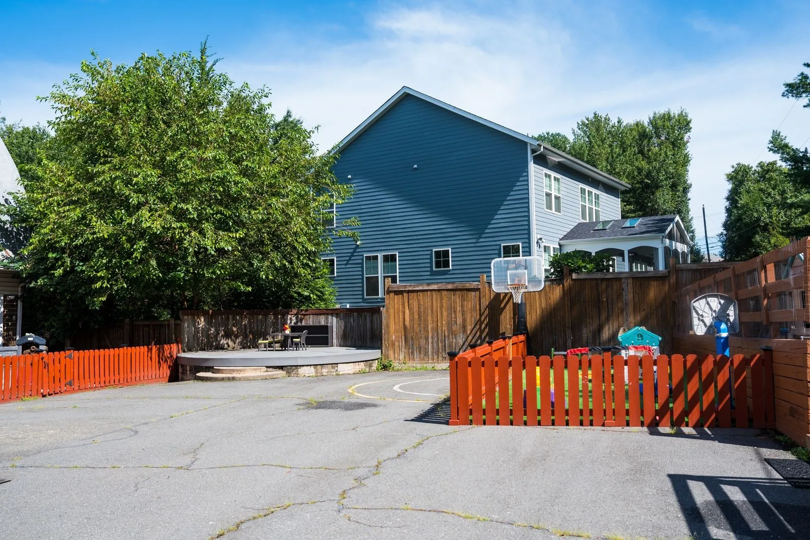The paved play yard with a basketball hoop and the fenced play areas