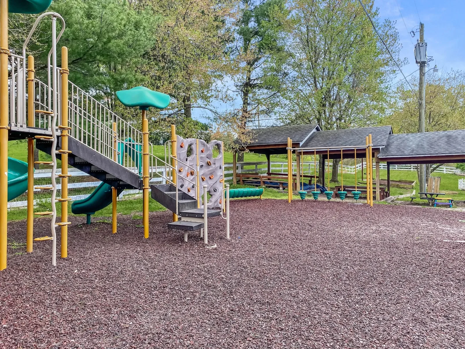 The large playground structure with a rock wall, ramp, and slides