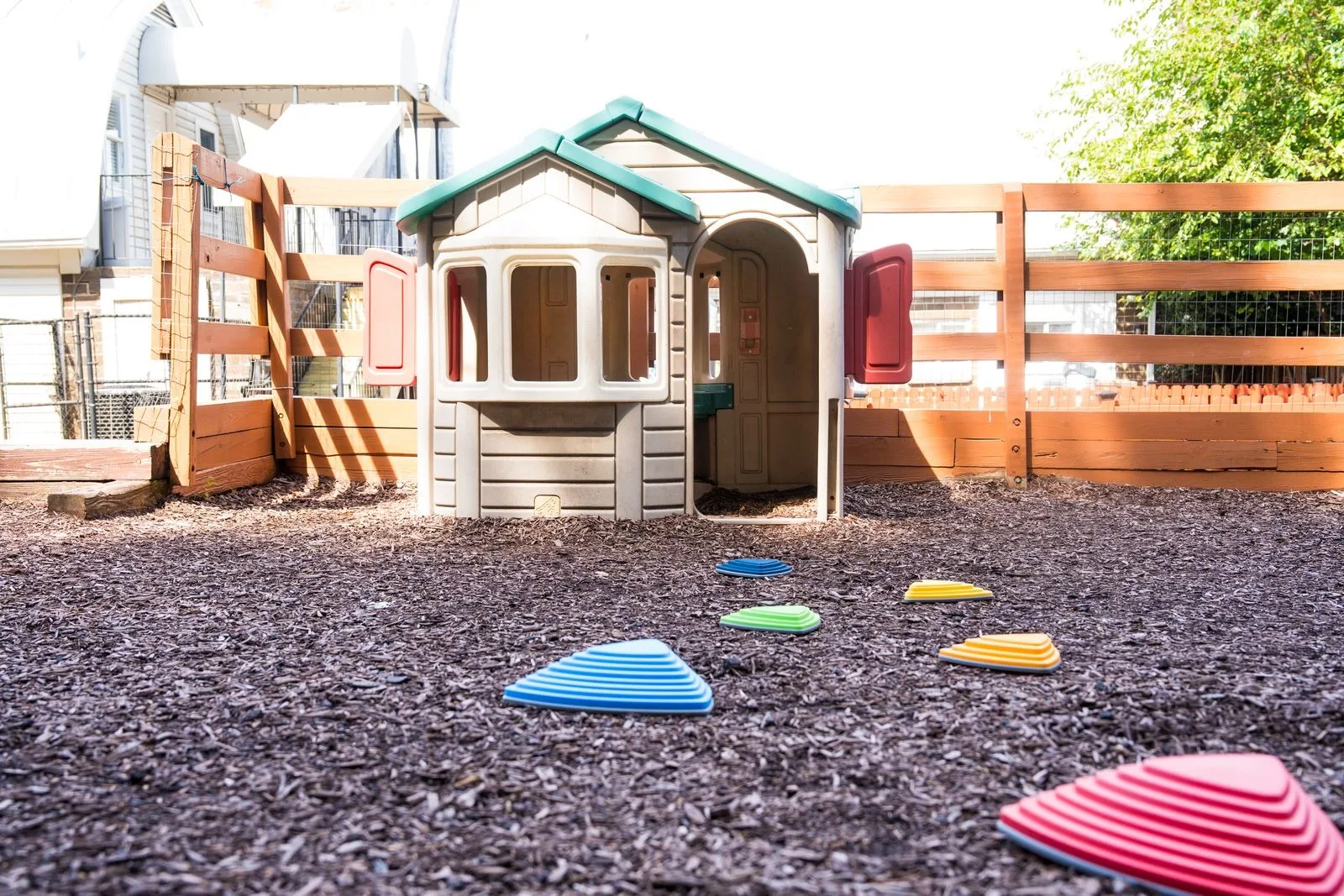 A playhouse and a line of stepping stones on the mulched play area