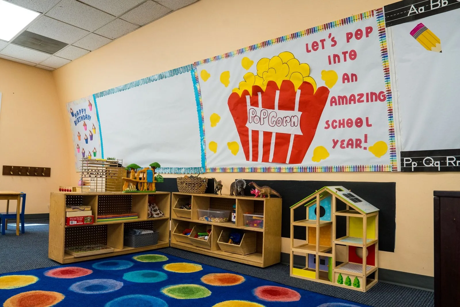 Pre-K learning centers with open shelving, a doll house, and the circles rug