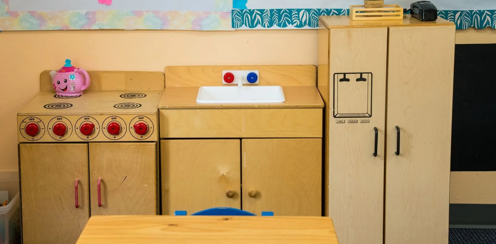 The Pre-K play kitchen with a stove, sink, and refrigerator