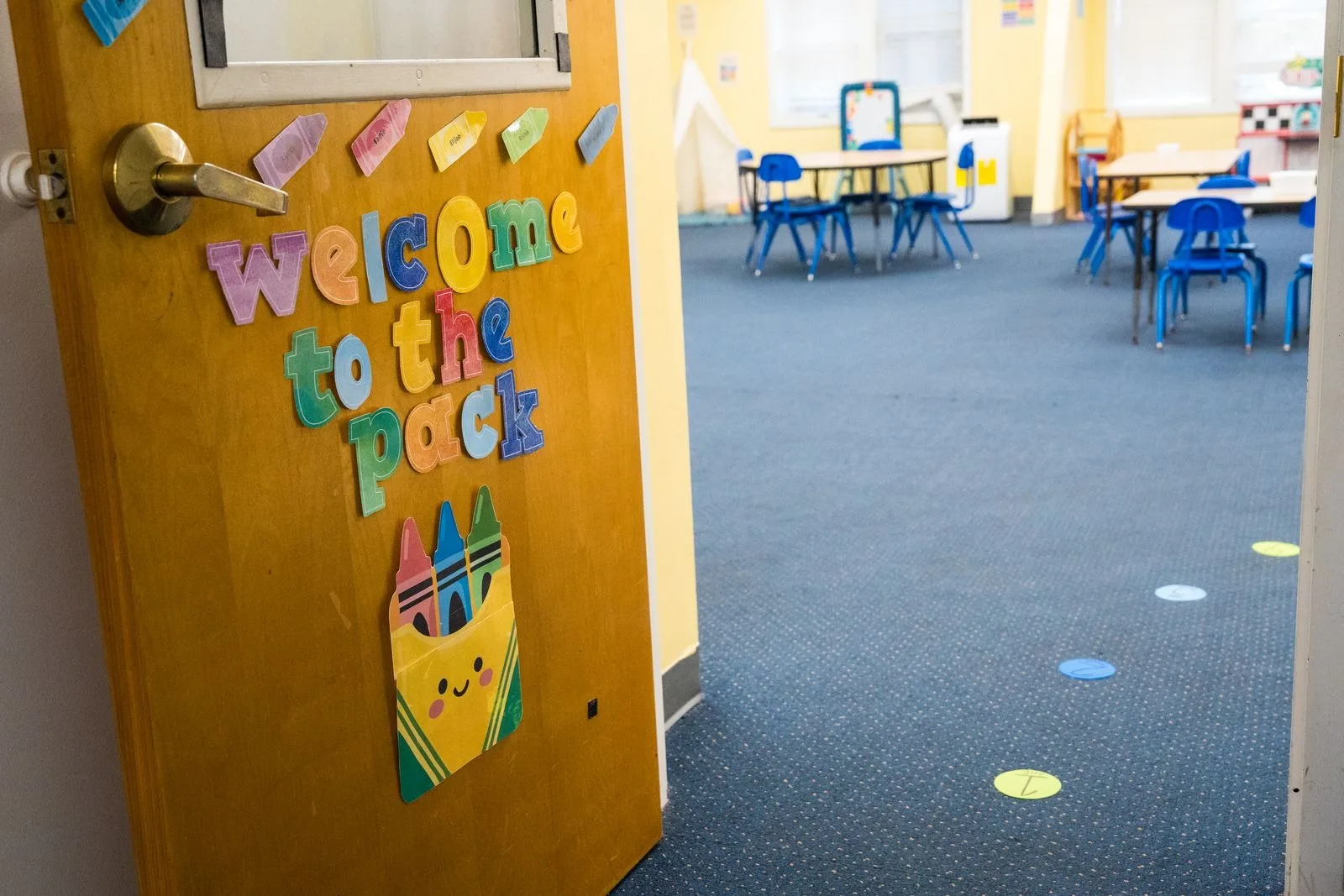 The preschool classroom door, decorated by the children, open onto the room