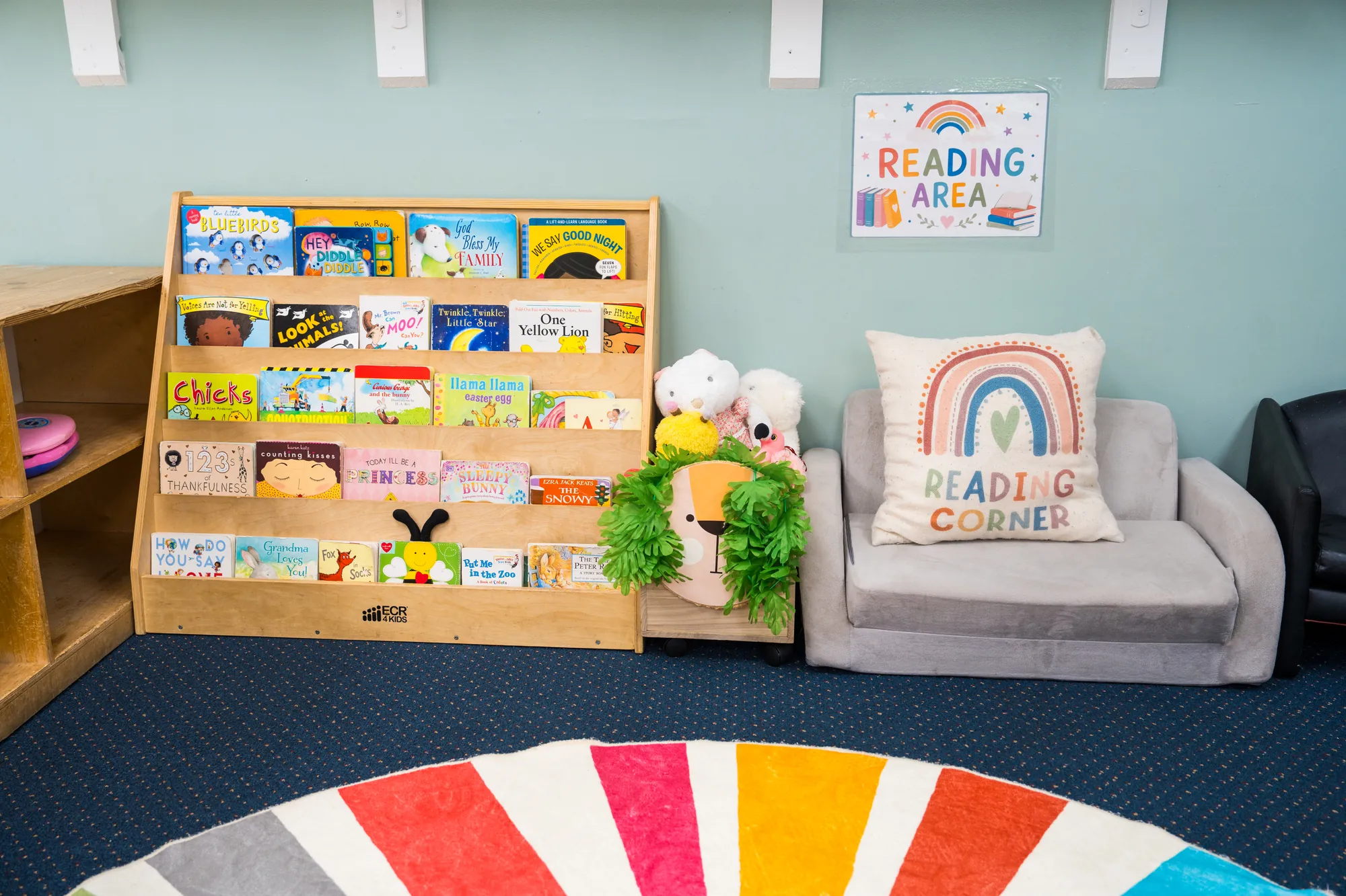 Toddler reading corner with a book display, soft couch, and Reading Corner cushion